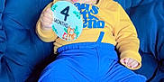 Priyansh Minhas is registered to the contest to win money with this photo: baby, infant, child, blue_pants, yellow_sweater, cushion, chair, holding_sign, 4_months, milestone, cute, indoors, portrait, feet, hand, face, clothing, sitting, young, resting