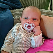 Yuna joined the competition — help win amazing prizes! baby, pacifier, infant, clothing, blanket, cushion, person, face, hand, adult, pink_clothing, blue_cushion, resting, indoors, portrait, expression, comfort, closeup, skin, sleepwear