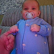 Yuna joined the competition — help win amazing prizes! baby, pacifier, blue_onesie, bee_pattern, hand, finger, cushion, blanket, floor, carpet, indoor, person, infant, child, smiling, closeup, cozy, cute, sleepwear, relaxed