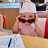 Alessi joined the competition — help win amazing prizes! toddler, child, sunglasses, paper_hat, coloring_sheet, crayons, pen, diner, table, chair, person, smiling, playful, indoor, food_counter, retro, casual, seat, cute, family