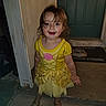 Alessi is registered to the contest to win money with this photo: child, toddler, yellow_dress, smile, standing, doorstep, blue_door, sandals, outdoor, happy, face, person, evening, hair, concrete, mat, patterned_dress, cute, small_child, front_door