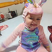 Alessi joined the competition — help win amazing prizes! baby, bed, blanket, child, costume, cute, furniture, happy, headwear, indoor, person, pink_clothing, playful, portrait, room, sitting, smile, soft_toys, toddler, unicorn_costume