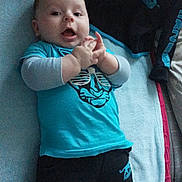 Kays a rejoint le concours — aidez-le/la à gagner de superbes lots ! baby, child, infant, blue_shirt, pants, lying_down, towel, indoor, smiling, hands, cute, person, young_child, clothing, happy, face, skin, socks, casual, expression