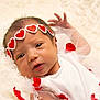 baby, newborn, infant, headband, red_hearts, white_clothing, blanket, soft_texture, cute, portrait, lying_down, small_hands, face, eyes_open, tulle, fabric, adorable, child, closeup, gentle