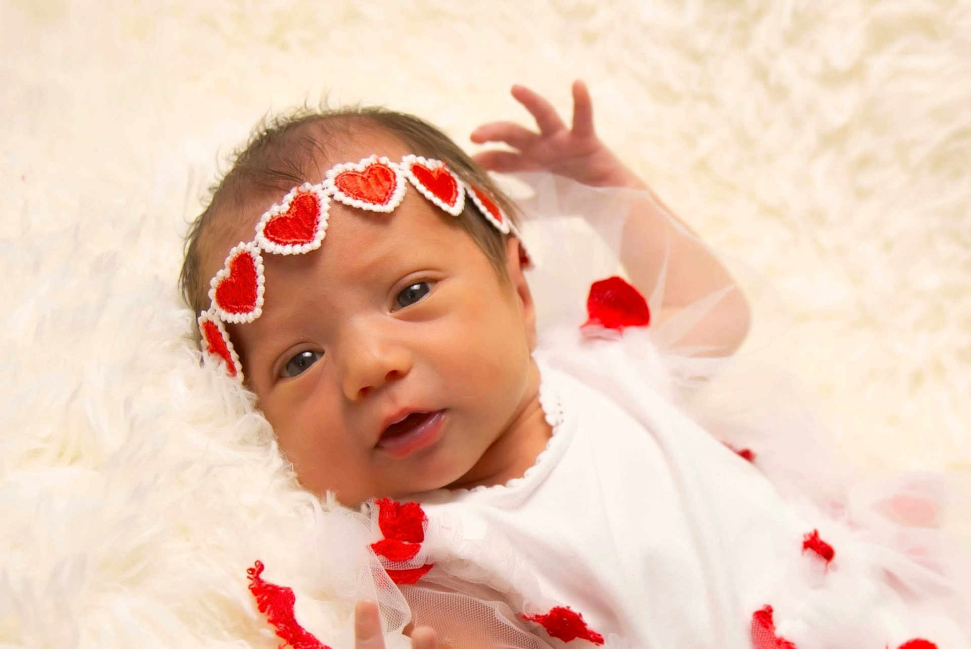 Rubyrae is registered to the contest to win money with this photo: baby, newborn, infant, headband, red_hearts, white_clothing, blanket, soft_texture, cute, portrait, lying_down, small_hands, face, eyes_open, tulle, fabric, adorable, child, closeup, gentle