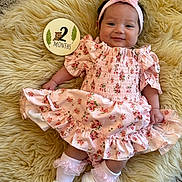 Rubyrae is registered to the contest to win money with this photo: baby, infant, girl, pink_dress, headband, smile, lying_down, fluffy_rug, milestone_sign, 2_months, white_booties, socks, flower_pattern, cute, portrait, child, indoors, soft_texture, happy, small