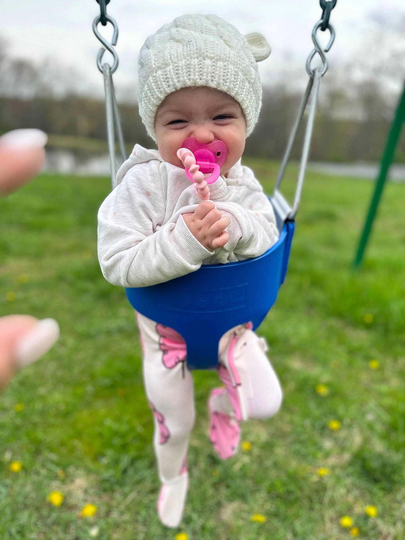 Briar is registered to the contest to win money with this photo: baby, baby_toddler_clothing, cap, child, eye, fun, grass, happy, headwear, leisure, people_in_nature, person, photograph, pink, playground, recreation, skin, sky, smile, swing