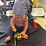 Aiden joined the competition — help win amazing prizes! baby, child, bandana, tape_measure, toy, floor, blanket, indoor, stroller, sign, pants, bare_chest, foot, hand, curious, sitting, black_blanket, yellow, blue, tile_floor