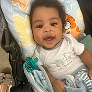 Aiden joined the competition — help win amazing prizes! baby, child, smiling, curly_hair, blanket, stroller, onesie, animal_print, pillow, cute, happy, infant, clothing, indoor, portrait, toddler, pacifier, hand, face, cozy