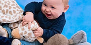 Jackson joined the competition — help win amazing prizes! baby, child, blue_background, plush_toys, giraffe_toy, elephant_toy, monkey_toy, smiling, happy, cute, soft_texture, jeans, long_sleeve_shirt, playful, indoor, childhood, portrait, infant, cuddly, light_skin