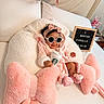 Fiorella is registered to the contest to win money with this photo: baby, pink, robe, headband, sunglasses, starbucks_cup, cushion, bow, bed, pillow, letter_board, indoor, child, smile, cozy, cute, infant, footwear, person, celebration
