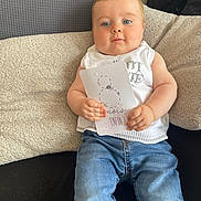 Mylo a rejoint le concours — aidez-le/la à gagner de superbes lots ! baby, child, blue_eyes, jeans, white_top, card, couch, cushion, blanket, indoor, person, portrait, sitting, hands, face, milestone_card, cozy, cute, relaxed, soft_texture