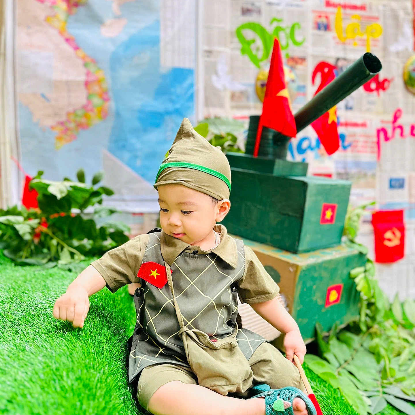 Meo is registered to the contest to win money with this photo: accessories, bag, boy, cap, child, clothing, costume, face, grass, handbag, hat, head, male, military, militaryuniform, pants, person, plant, sitting, student