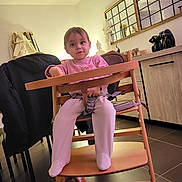Lauëline participe au concours pour gagner de l'argent avec cette photo : child, toddler, highchair, baby, indoor, living_room, mirror, dresser, statue, toy, pink_clothing, socks, wooden_chair, tray, seatbelt, floor_tiles, coat, lamp, portrait, curiosity