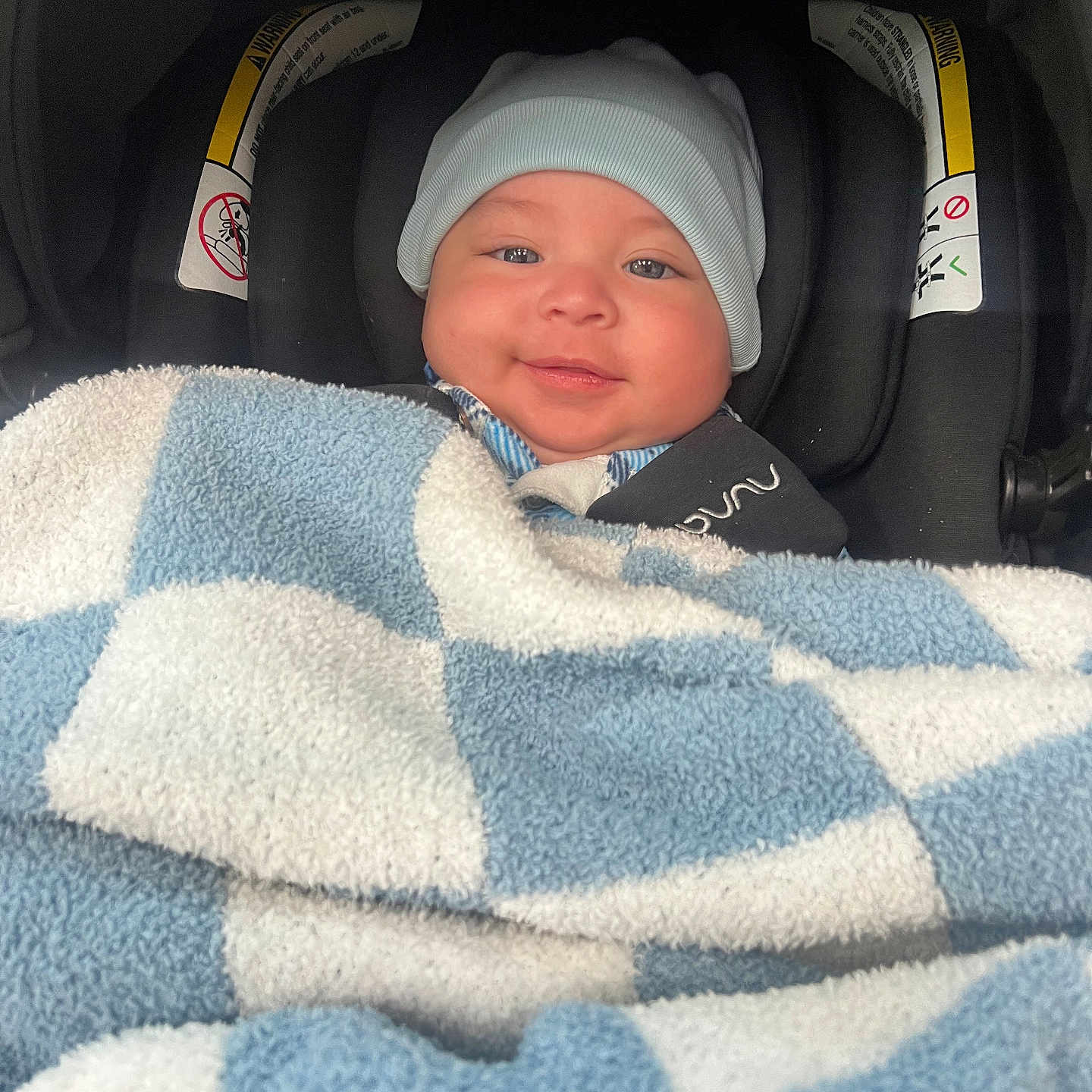 Adriel joined the competition — help win amazing prizes! baby, blanket, blue, car_seat, child, comfort, cozy, cute, face, hat, headwear, indoors, infant, person, portrait, seatbelt, smiling, toddler, warm, white