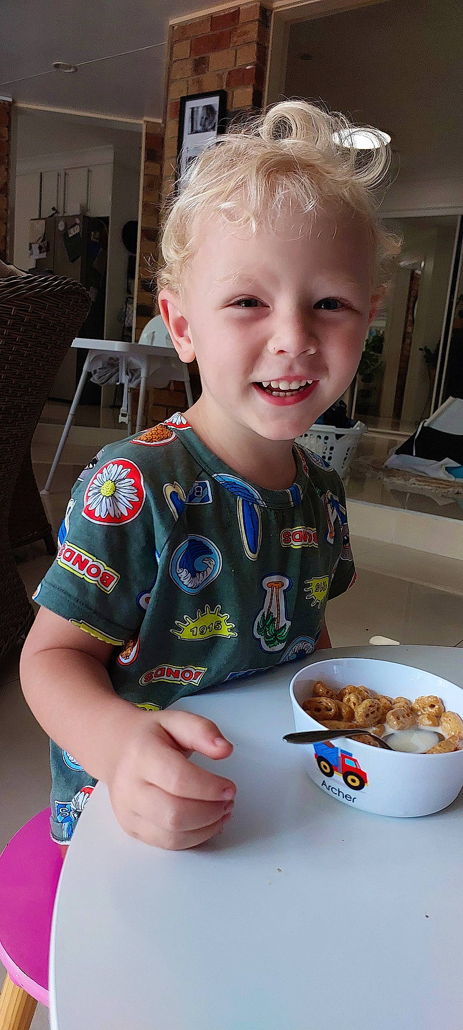 Archer is registered to the contest to win money with this photo: baby_toddler_clothing, chair, cheek, child, chin, clothing, comfort_food, cooking, dishware, event, face, food, food_craving, happy, joy, person, plate, smile, t_shirt, table