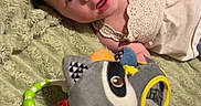 Madeline is registered to the contest to win money with this photo: baby, baby_wipes, blanket, blue_eyes, child, clothing, cute, face, green_blanket, hand, indoor, infant, lying_down, mirror, plush_toy, raccoon_toy, soft_texture, toy, white_dress, winnie_the_pooh