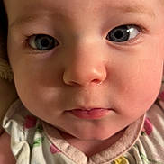 Madeline is registered to the contest to win money with this photo: baby, face, blue_eyes, close_up, infant, child, skin, expression, portrait, cute, clothing, floral_pattern, young_child, person, head, looking_at_camera, indoors, soft_lighting, skin_texture, human
