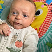 Chase joined the competition — help win amazing prizes! baby, infant, child, blue_eyes, face, hand, clothing, onesie, vegetable_patches, play_mat, colorful, yellow_character, cute, smiling, indoors, portrait, closeup, soft_lighting, expression, person