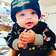 Anthony Casique is registered to the contest to win money with this photo: baby, child, infant, clothing, black_beanie, mexico, hands, face, indoor, cute, smiling, person, portrait, sitting, bright_eyes, young, warm, apparel, adorable, expression