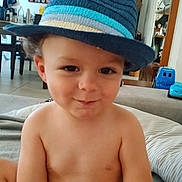 Elliott a rejoint le concours — aidez-le/la à gagner de superbes lots ! toddler, child, hat, fedora, blue, striped, smile, indoor, living_room, toy, diaper, cheeky, face, person, shirtless, curly_hair, home, furniture, couch, playful