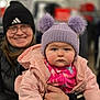 Macie is registered to the contest to win money with this photo: adult, baby, beanie, blurred_background, child, cute, glasses, hat, holding, indoor, jacket, person, pink, pom_poms, portrait, purple, smile, store, warm, winter_clothing