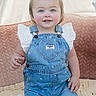 toddler, child, denim_overalls, blue_eyes, rosy_cheeks, kneeling, blanket, soft_texture, indoor, cute, smiling, clothing, white_shirt, baby, portrait, face, person, hair, young_child, innocence