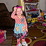 Gracelyn joined the competition — help win amazing prizes! toddler, child, smiling, indoor, playroom, toys, bookshelf, curtains, striped_clothing, socks, pink_sunglasses, carpet, couch, wooden_floor, bag, playful, happy, person, furniture, living_room
