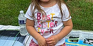 Gracelyn is registered to the contest to win money with this photo: box, casual, child, clothing, cute, daylight, girl, grass, happy, leaf, nature, outdoor, person, plant, portrait, sitting, skirt, smiling, tshirt, water_bottle