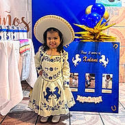 Xolani joined the competition — help win amazing prizes! balloons, blue_background, celebration, child, cute, decorated_table, dress, embroidery, event, festive, floor_tiles, happy, hat, indoor, person, photography, portrait, smiling, traditional_clothing, young