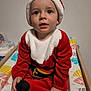 Arthur a rejoint le concours — aidez-le/la à gagner de superbes lots ! baby, changing_mat, child, christmas_costume, colorful_pattern, curious_expression, cute, face, festive, headwear, holiday, indoor, person, portrait, red_clothing, santa_hat, sitting, toddler, white_fur_trim, young_child