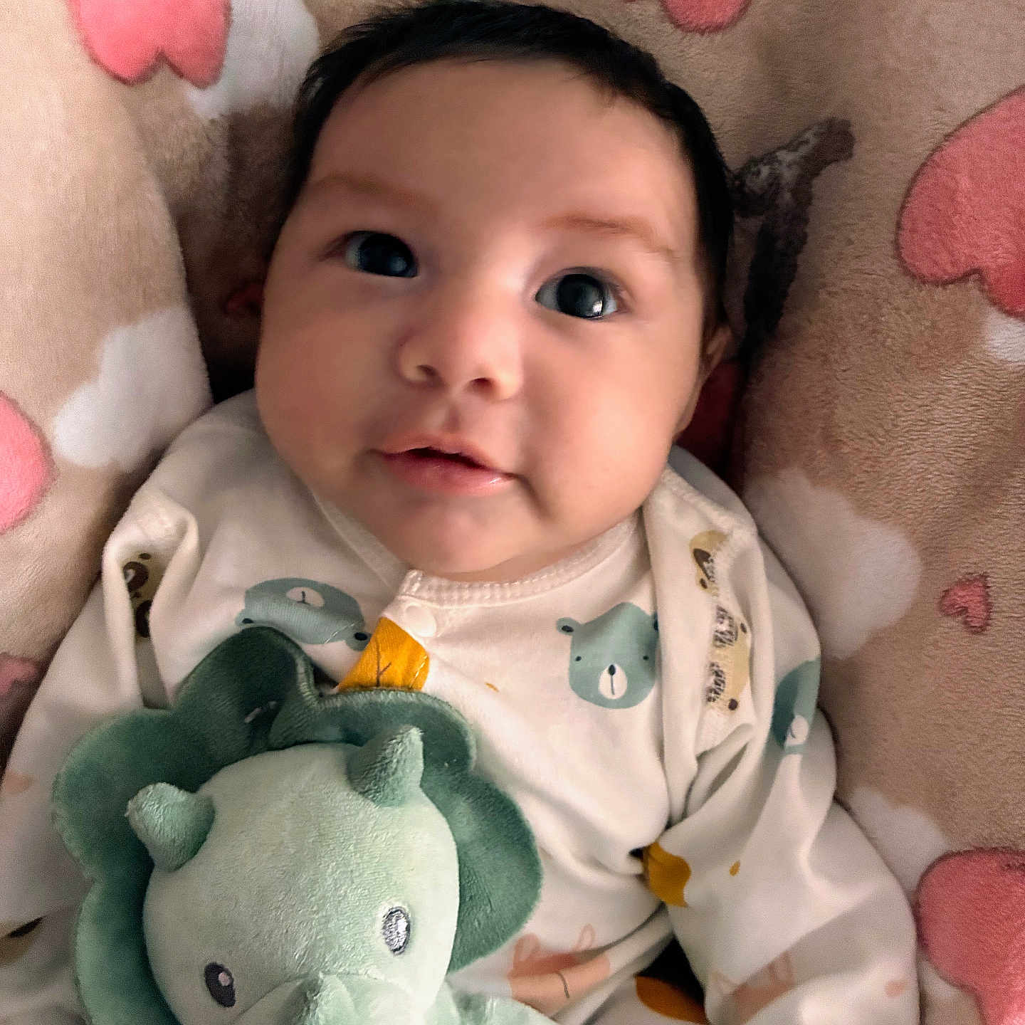 Luis joined the competition — help win amazing prizes! baby, infant, child, portrait, lying_down, plush_toy, dinosaur, stuffed_animal, blanket, bed, cozy, indoors, cute, wide_eyed, dark_hair, onesie, baby_clothing, pastel_colors, close_up, smiling