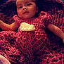 baby, child, dress, hand_knitted, pink, flower, blanket, lying_down, soft_lighting, indoors, comfort, portrait, infant, cute, clothing, person, cozy, warm_colors, fabric, relaxation