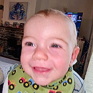 Bodhi joined the competition — help win amazing prizes! toddler, child, smile, face, bib, clothing, indoor, living_room, television, fireplace, stone, toy, happy, person, head, eyes, hair, cheeks, baby, home