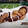 Omar is registered to the contest to win money with this photo: baby, sleeping, football, crocheted_clothing, hat, leg_warmer, blanket, sports_theme, infant, field, helmet, blurred_background, cute, resting, portrait, newborn, soft_texture, child, sports, cozy