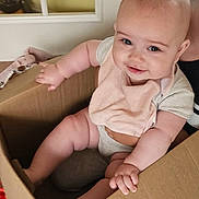 Scarlett joined the competition — help win amazing prizes! baby, cardboard_box, indoor, smiling, bib, cute, child, person, sitting, chubby, happy, skin, face, hand, arm, leg, clothing, door, floor, household