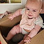 baby, cardboard_box, indoor, smiling, bib, cute, child, person, sitting, chubby, happy, skin, face, hand, arm, leg, clothing, door, floor, household