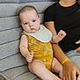 Kézio a rejoint le concours — aidez-le/la à gagner de superbes lots ! adult, baby, bib, black_shirt, casual, couch, expressionless, family, foot, furniture, grey_couch, hand, indoor, infant, onesie, person, relaxed, seated, skin, wristband