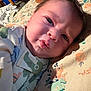 Jaeger is registered to the contest to win money with this photo: baby, infant, face, pajamas, lying_down, expression, closeup, skin, head, child, cute, indoors, fabric, pattern, floral, soft_lighting, person, newborn, sleepwear, cozy