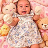 baby, infant, smiling, mittens, floral_dress, stuffed_animals, bunny, teddy_bear, chick, cloud_pillow, pink_blanket, heart_pattern, cute, happy, child, soft_toys, portrait, indoors, cozy, playful
