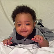 Serenity is registered to the contest to win money with this photo: baby, smiling, child, infant, lying_down, blanket, clothing, cute, face, portrait, happy, indoor, young_child, curly_hair, person, expression, toddler, studio, sleeves, hands