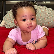 Serenity joined the competition — help win amazing prizes! baby, bed, child, curly_hair, cute, earrings, expression, eyes, face, furniture, hand, headboard, indoor, infant, lying_down, pillow, pink_onesie, portrait, red_bedspread, soft_lighting