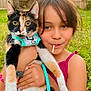 calico_cat, cat, child, cute, daylight, fence, girl, grass, harness, holding, leash, lollipop, nature, outdoor, pet, playful, portrait, smile, summer, tree