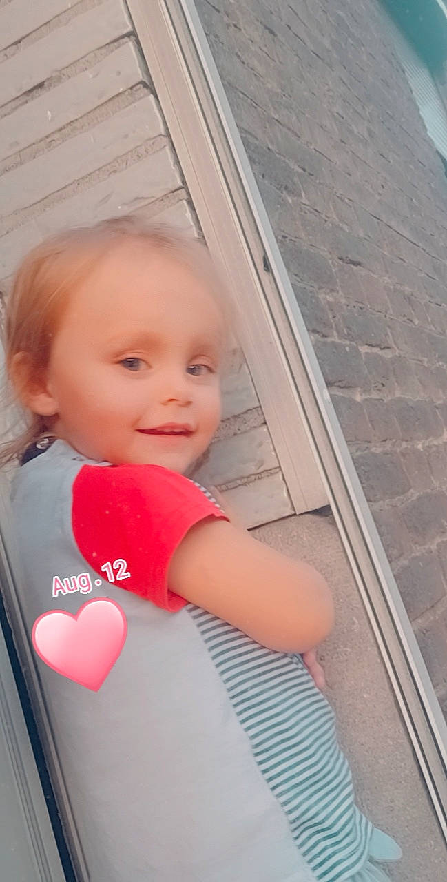 Felicia a rejoint le concours — aidez-le/la à gagner de superbes lots ! baby, baby_toddler_clothing, carmine, cheek, child, chin, eye, fun, happy, lip, magenta, material_property, person, sitting, skin, smile, t_shirt, toddler, vacation, window