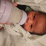 David joined the competition — help win amazing prizes! baby, bottle, feeding, blanket, newborn, infant, hand, milk, purple, clothing, face, person, lying_down, bed, soft, cute, sleepwear, skin, head, hair
