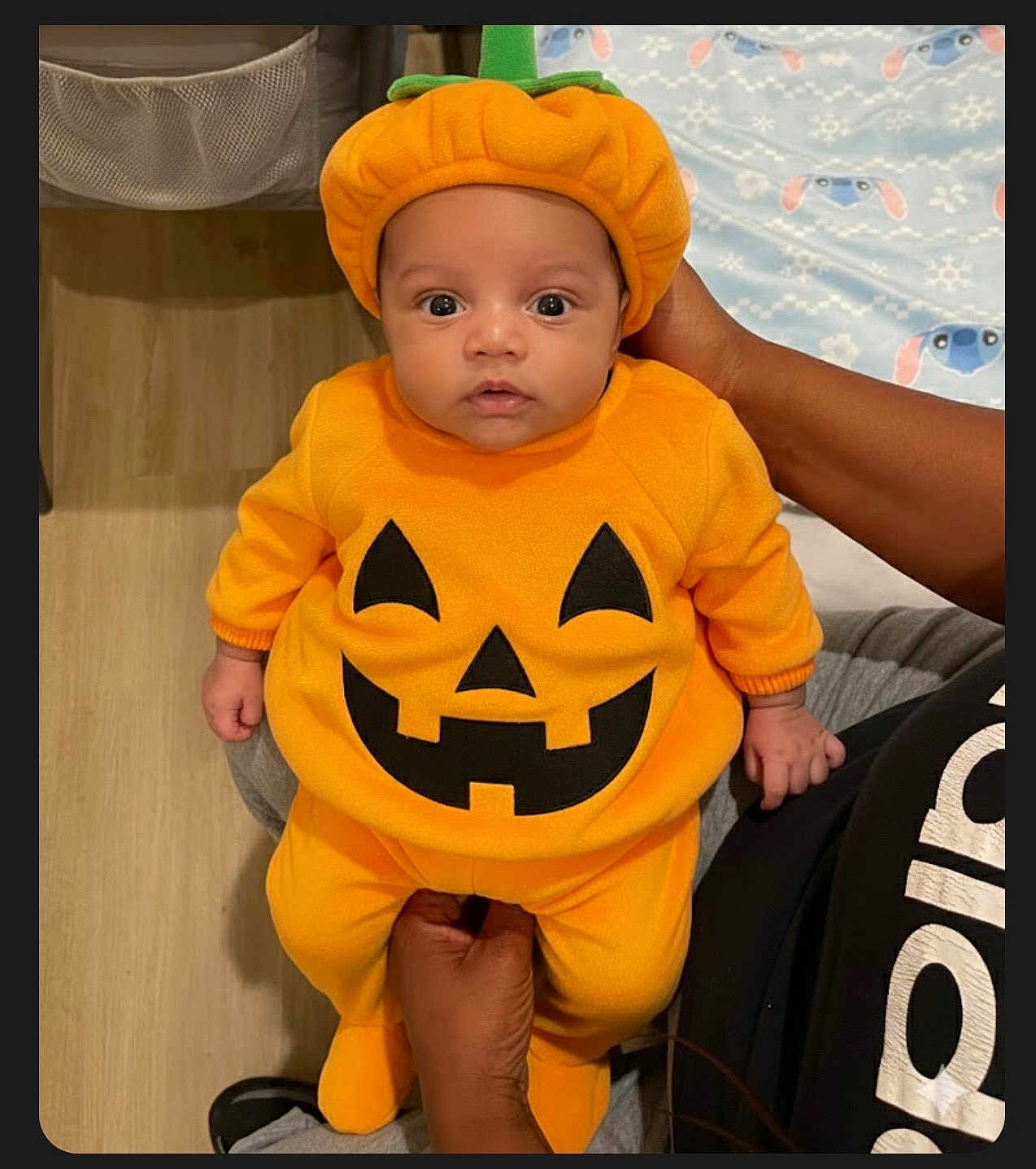 Layken is registered to the contest to win money with this photo: adult, baby, blanket, child, clothing, costume, cute, expression, floor, halloween, hand, hat, holiday, indoors, infant, orange, person, portrait, pumpkin_costume, sitting