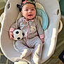 baby, infant, child, smiling, pajamas, baby_seat, toy, soccer_ball, headwrap, indoor, cushion, cozy, cute, happy, person, portrait, clothing, floor, lighting, relaxing
