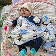 Vedanya Jain is registered to the contest to win money with this photo: baby, infant, hat, blanket, stars, play_mat, sock, mittens, smile, face, lying_down, toy, colorful, pattern, indoor, cute, cozy, child, person, soft