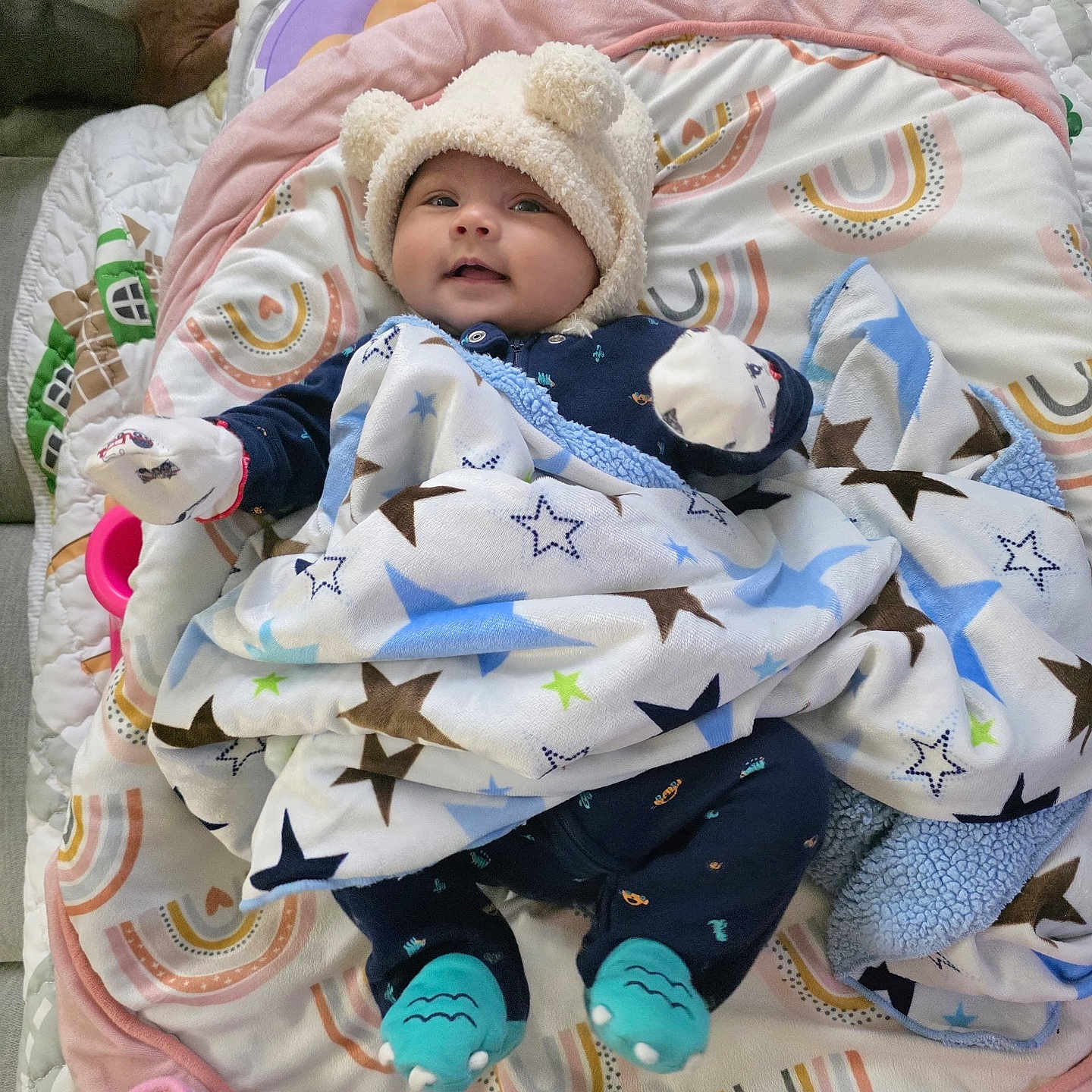 Vedanya Jain is registered to the contest to win money with this photo: baby, blanket, child, colorful, cozy, cute, face, hat, indoor, infant, lying_down, mittens, pattern, person, play_mat, smile, sock, soft, stars, toy