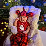 Vedanya Jain joined the competition — help win amazing prizes! baby, smiling, red_clothing, plaid_pants, christmas_tree, christmas_ornaments, holiday_lights, fluffy_blanket, festive, hat, infant, holiday, decorations, celebration, happy, indoors, seasonal, cozy, person, portrait